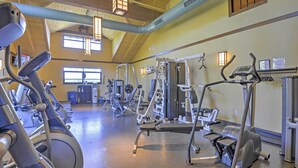Ein Fitnessstudio mit verschiedenen Trainingsgeräten, darunter Laufbänder und Kraftgeräte, und großen Fenstern, die für natürliches Licht sorgen.