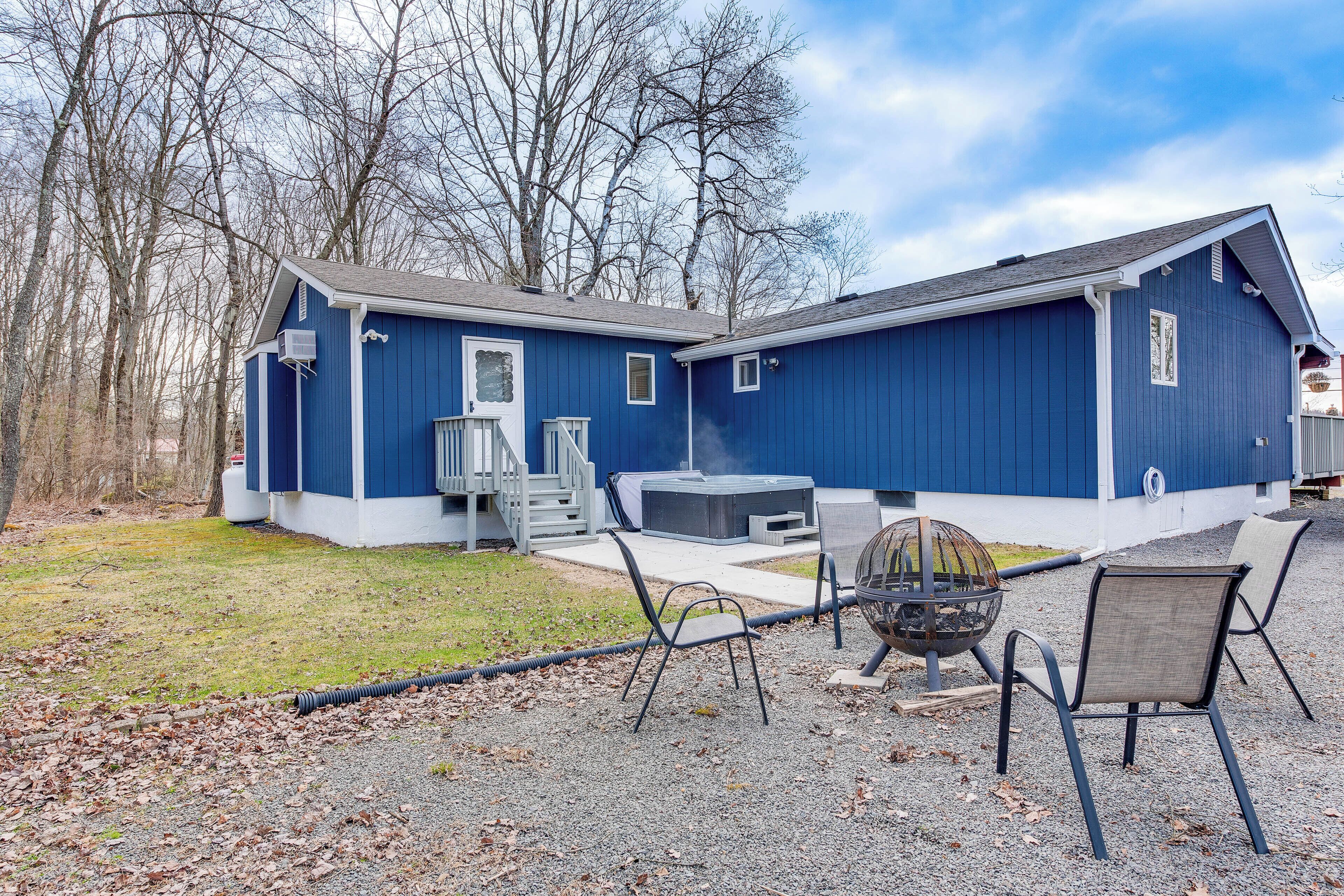 A blue house with a patio area, outdoor seating, and a fire pit.