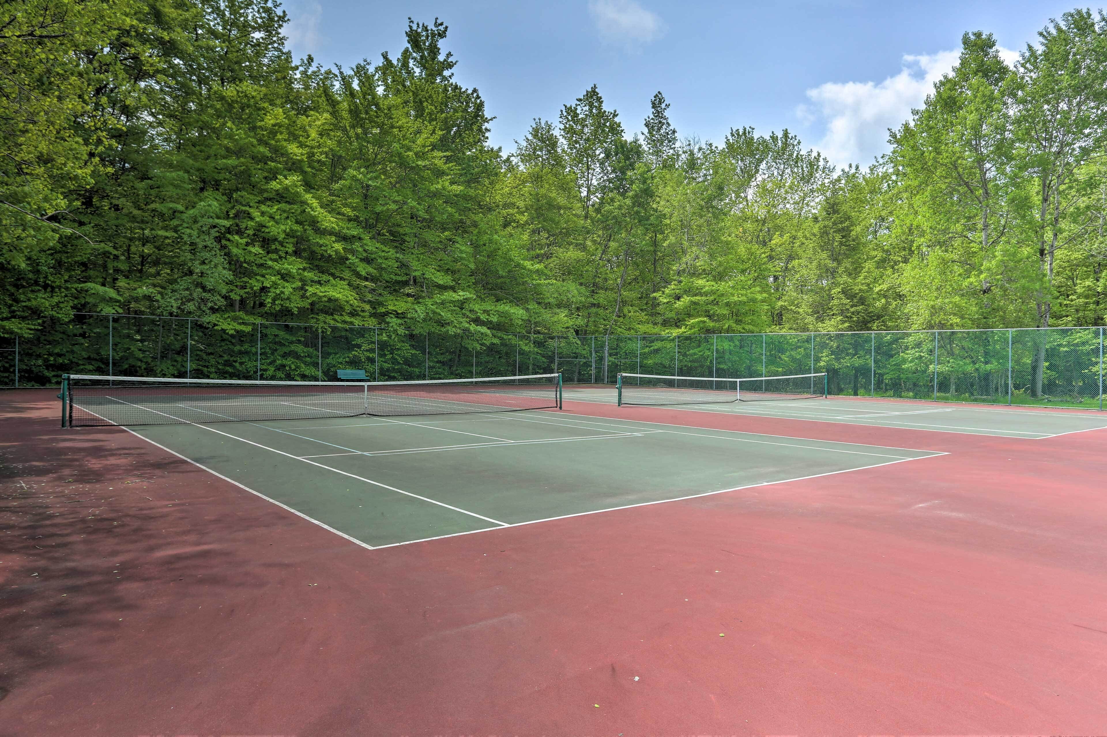 Tenniskenttä, jonka keskellä on verkko, ja jonka ympärillä on puita.