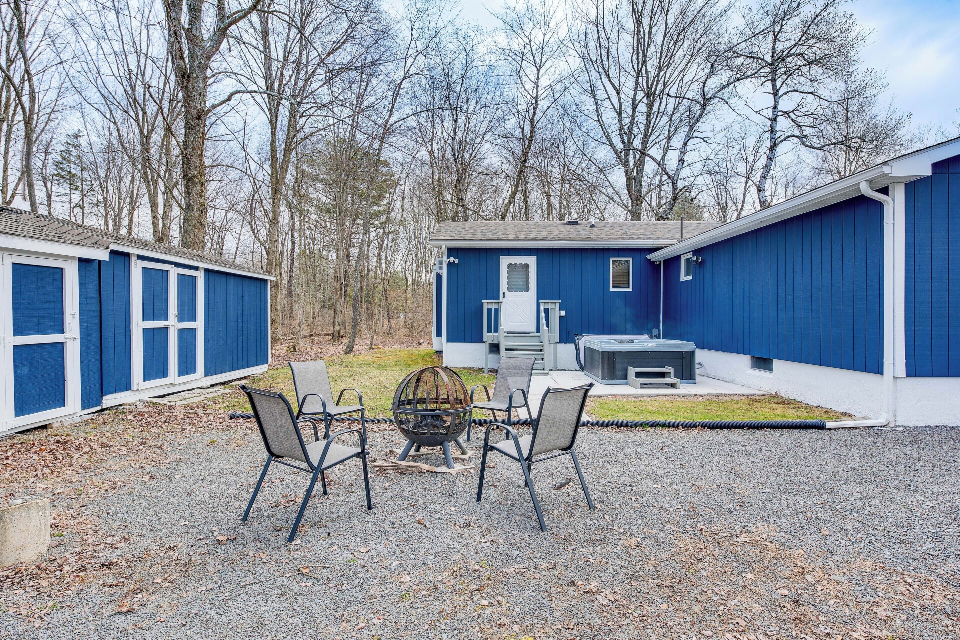 A building with a blue exterior, a fire pit with chairs in front, and a small table.