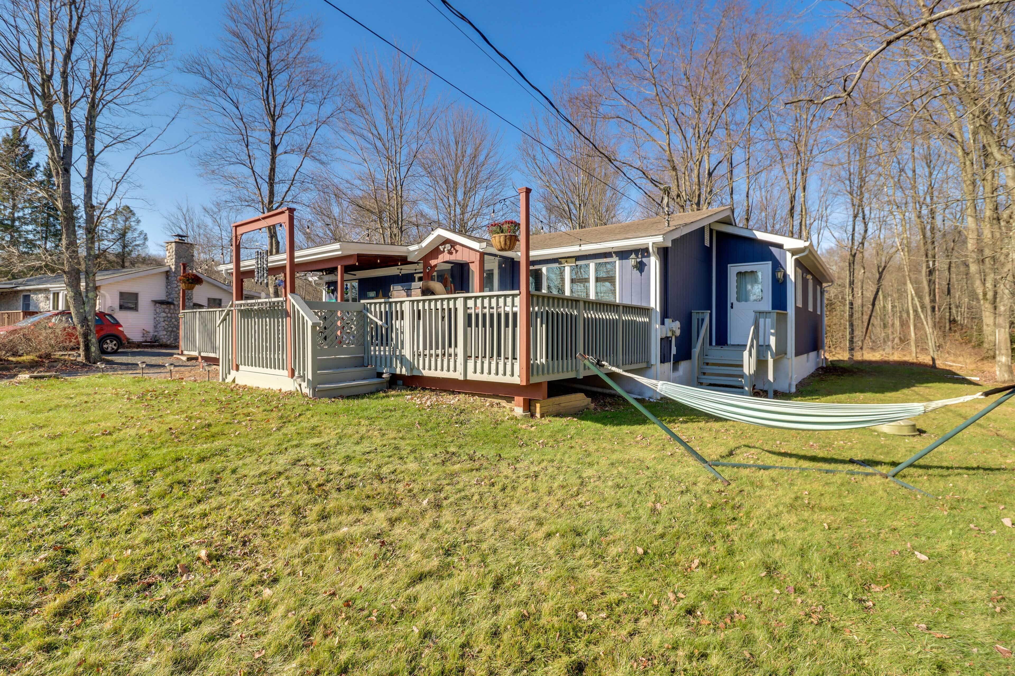 A two-story house with a porch, a small deck, and a hammock.