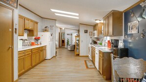 Una cocina con armarios de madera, un refrigerador y un microondas.