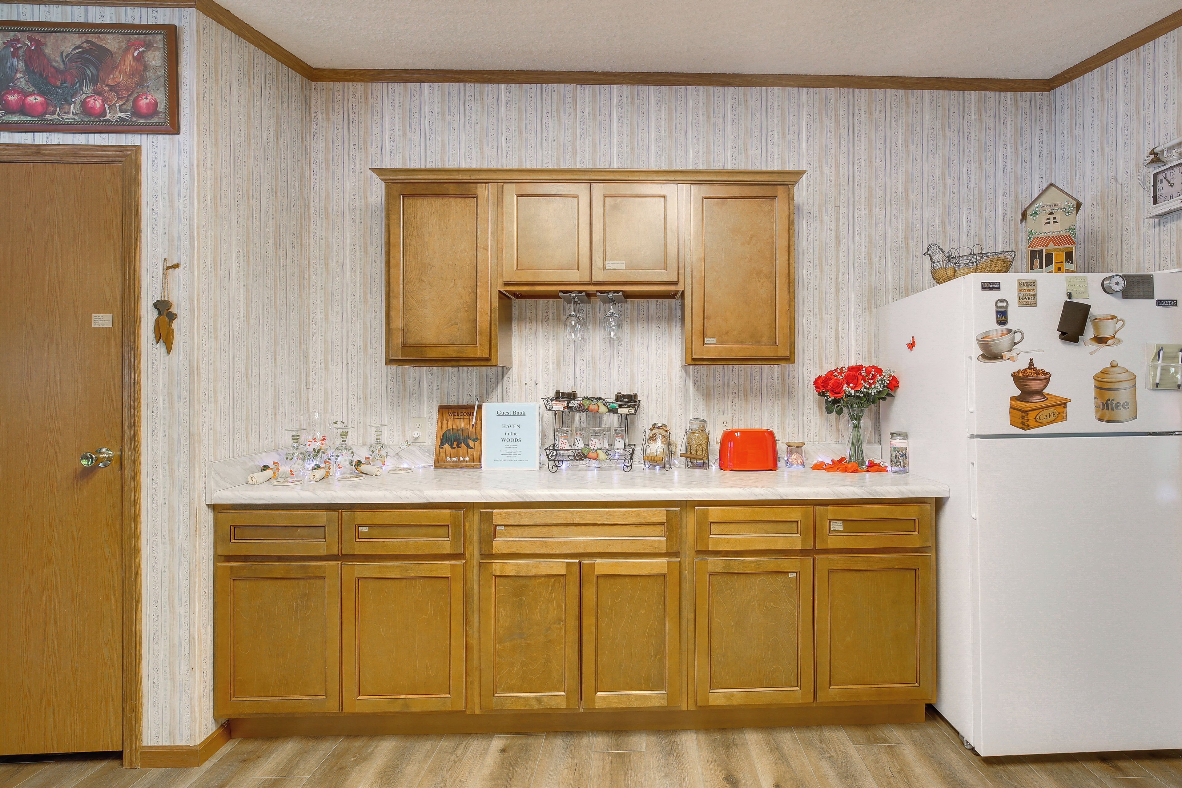 A kitchen with wooden cabinets, a white countertop, and a refrigerator.