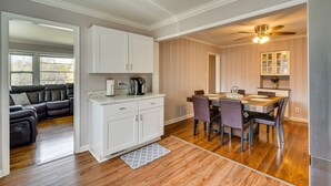 A modern kitchen with white cabinets, a dining table with chairs, and a ceiling fan. - Home Rental w/ Yard Near Downtown Greensboro! (Greensboro)