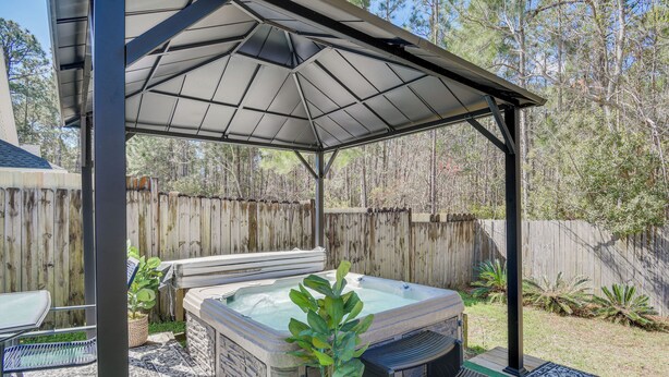 A covered outdoor hot tub area with a pergola, a seating area, and a wooden fence in the background. - Orange Beach Home w/ Hot Tub < 2 Mi to The Wharf (Orange Beach)