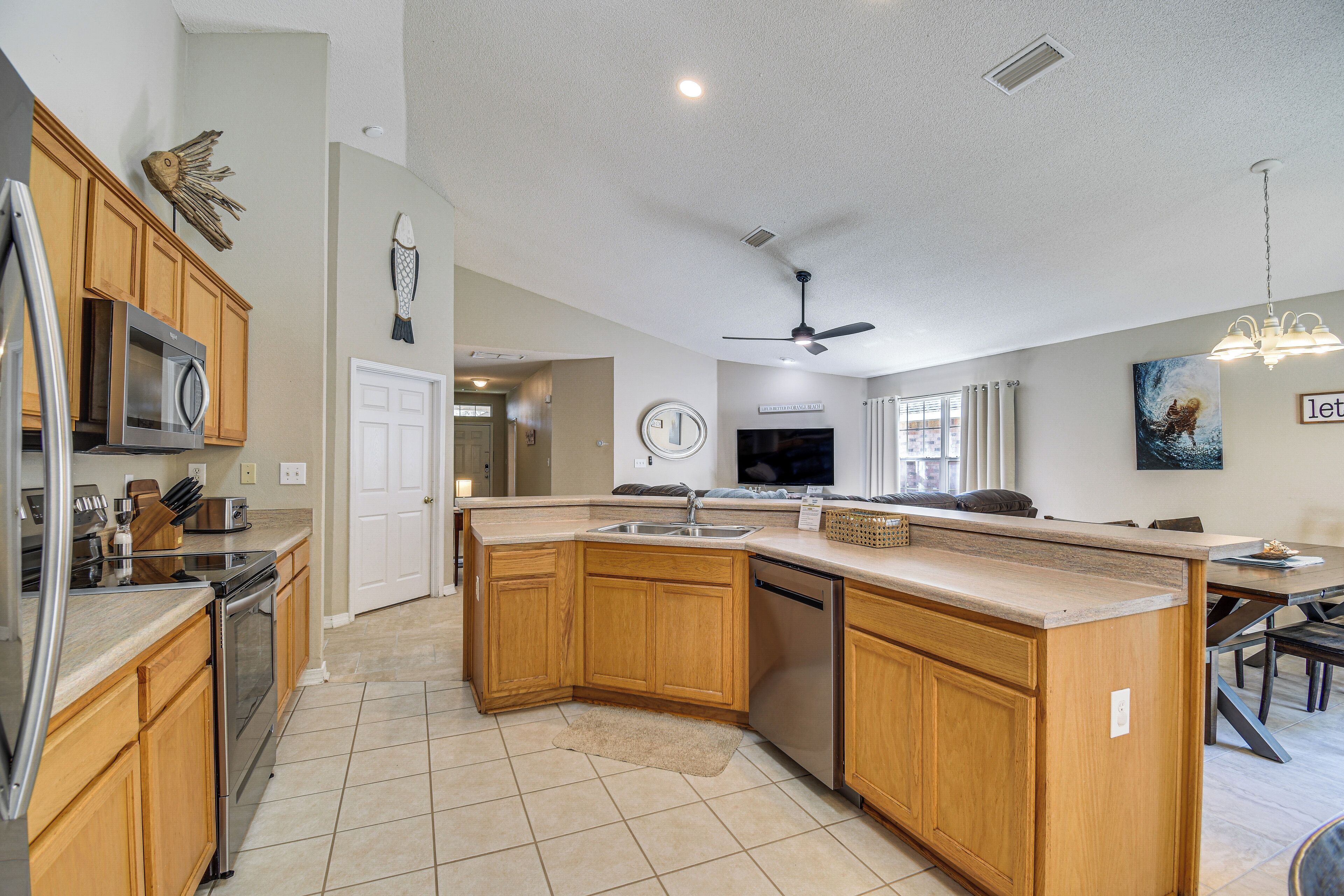 A spacious kitchen with wooden cabinets, a dishwasher, a microwave, and a large island with a sink.