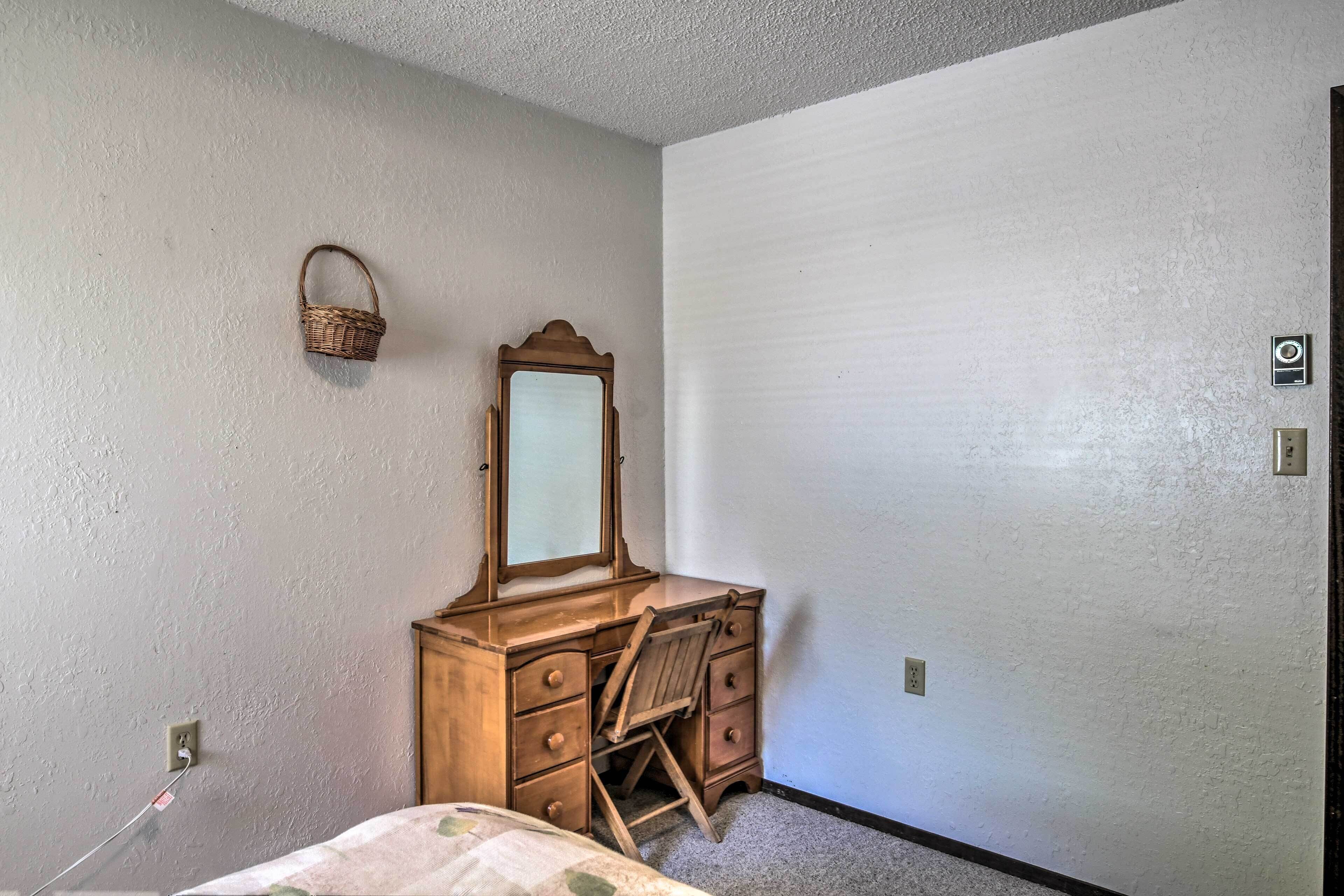 A bedroom with a wooden dresser, a mirror, and a bed.