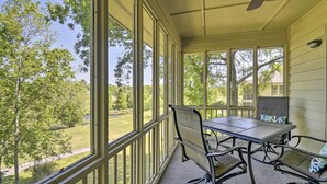 A covered patio with a table and chairs, large windows, and a view of a green landscape. - Sea Trail Resort Villas Condo w/ Community Perks! (Sunset Beach)