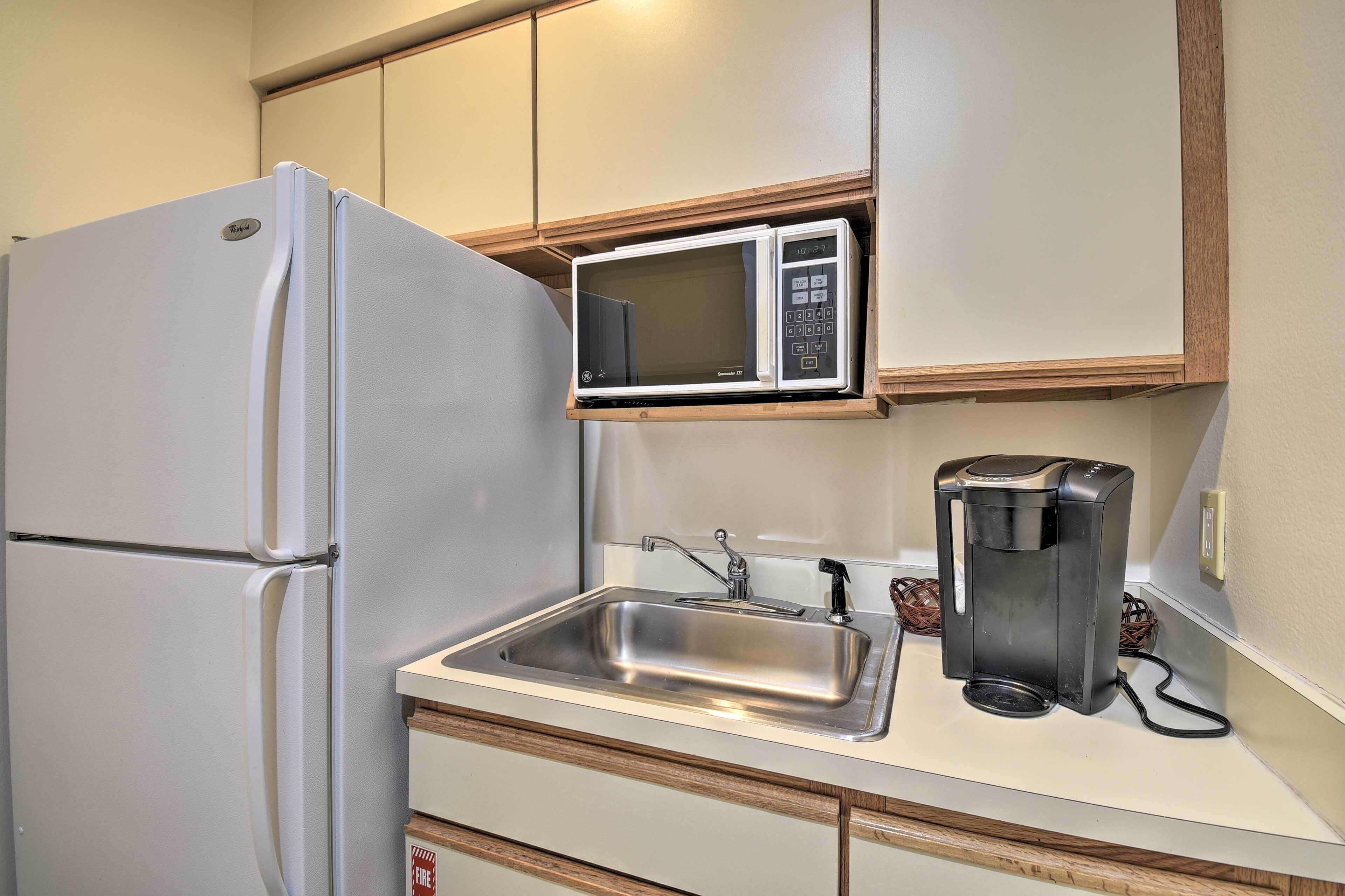 A compact kitchenette with a refrigerator, microwave, coffee maker, and sink.