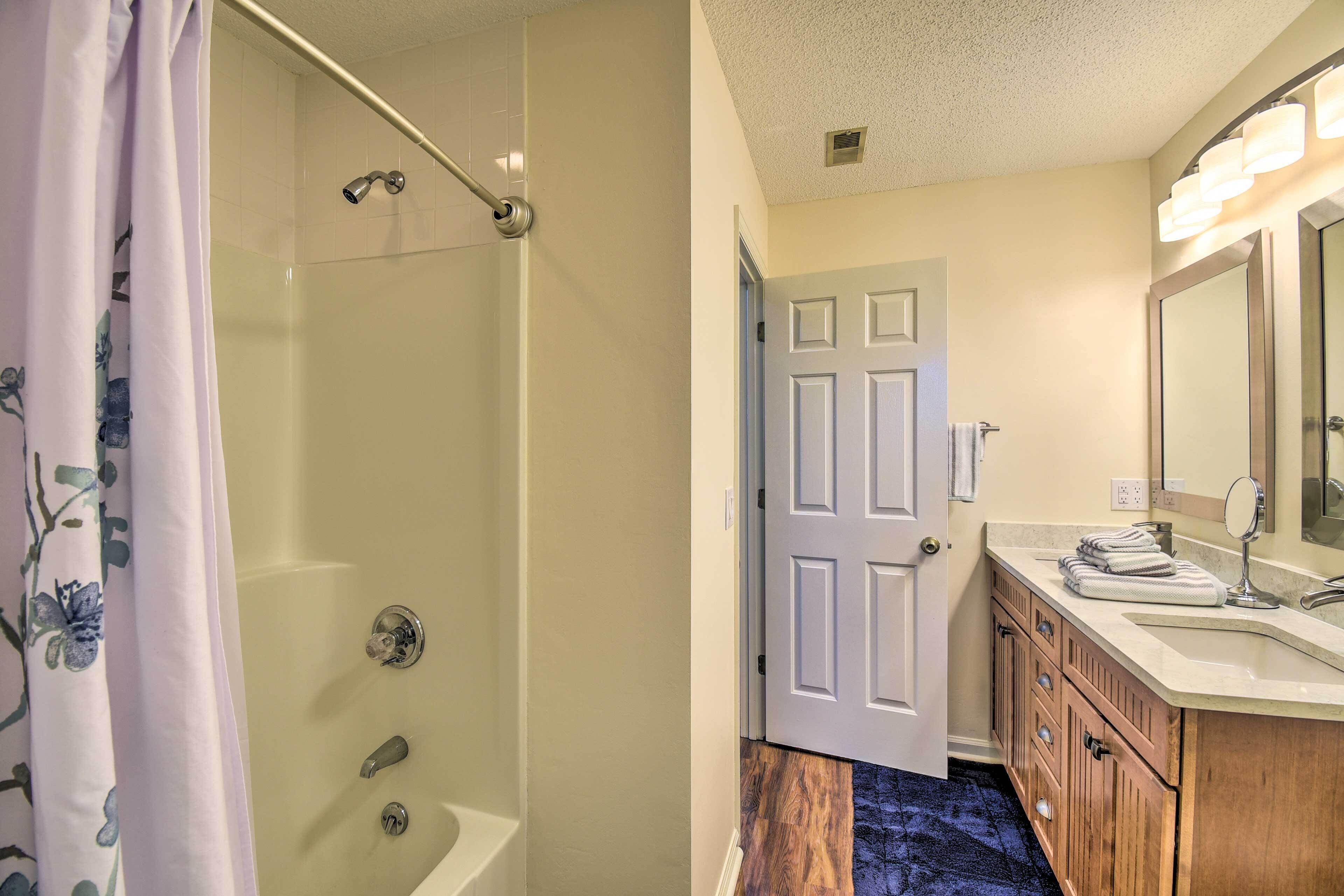 A bathroom with a shower, toilet, sink, and mirror.