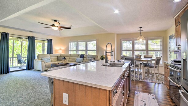 A spacious kitchen with a large island, wooden cabinets, and a dining area with a chandelier. - Sea Trail Resort Villas Condo w/ Community Perks! (Sunset Beach)