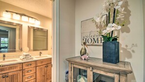 A bathroom with a wooden vanity, a large mirror, and a welcome home sign. - Sea Trail Resort Villas Condo w/ Community Perks! (Sunset Beach)