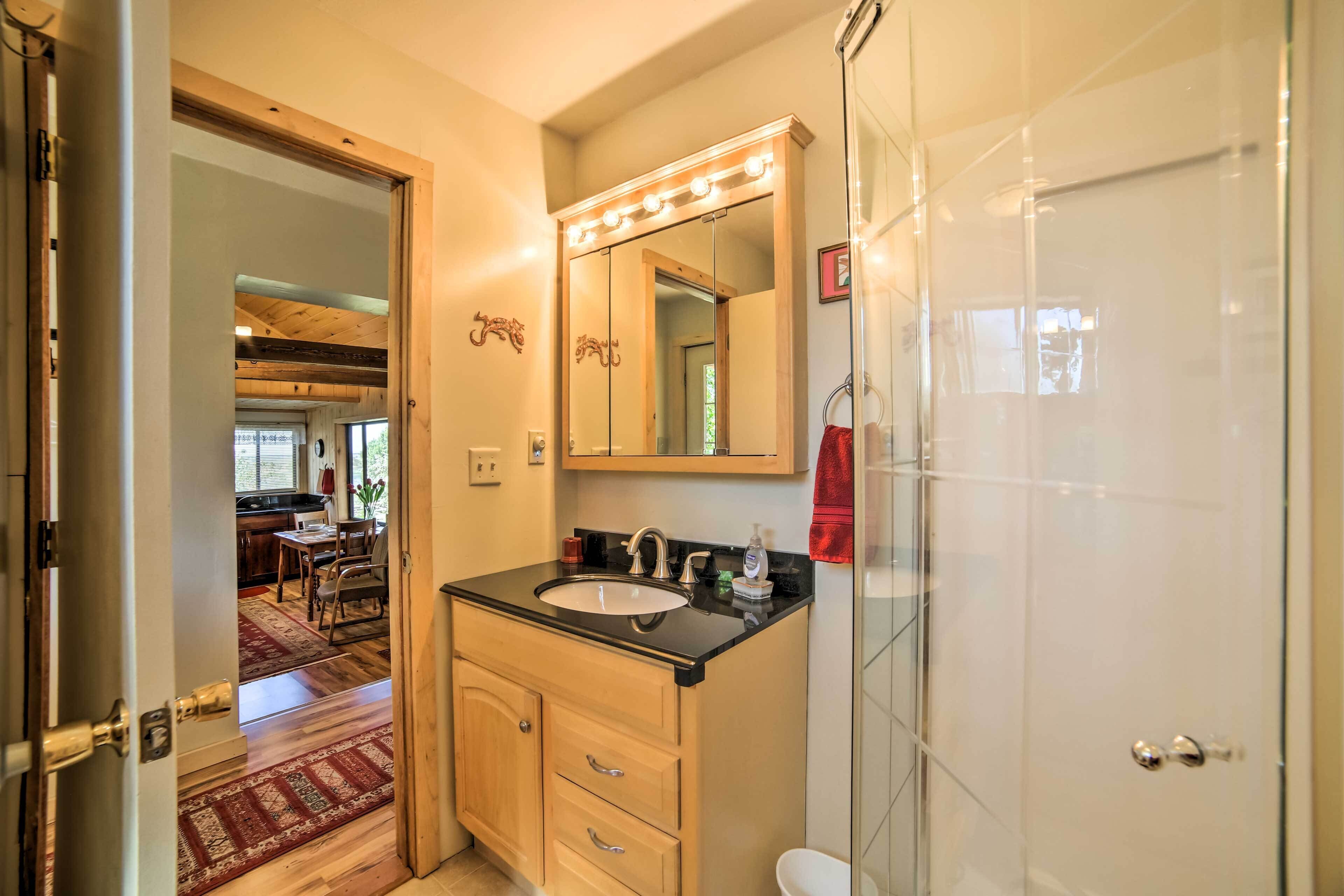 Een badkamer met een wastafel, spiegel en douche.