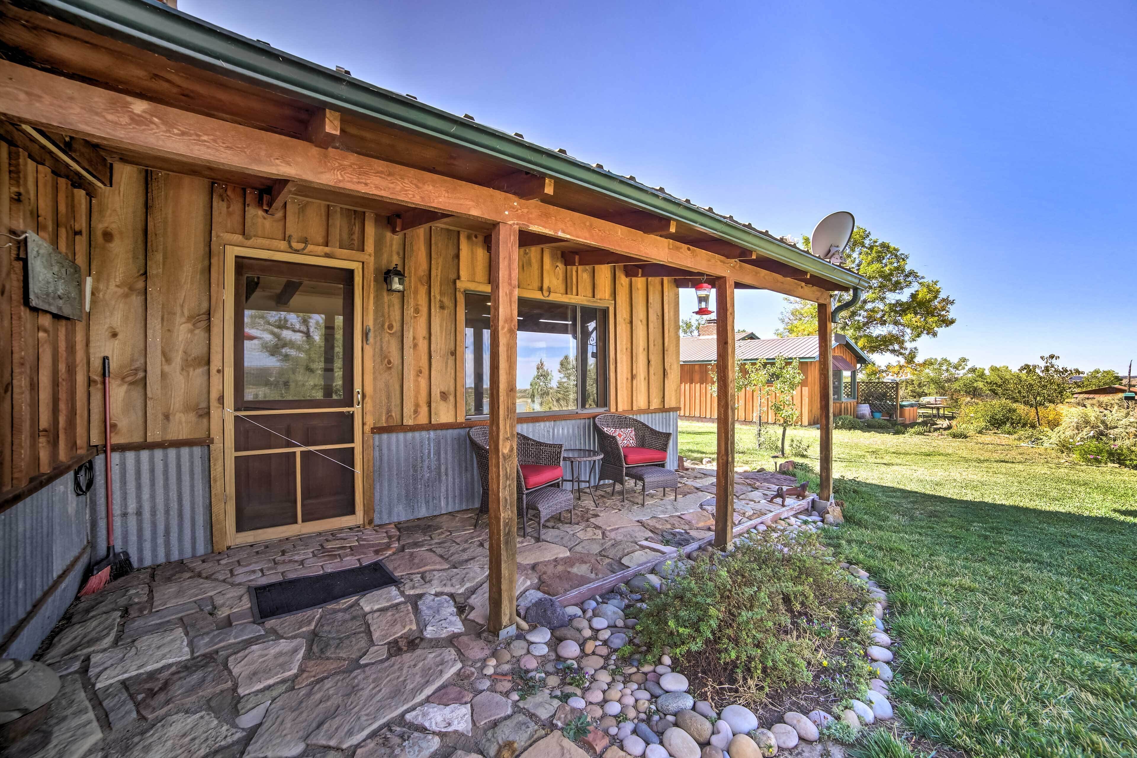 A wooden cabin with a stone-paved porch, a door, and a small garden area.