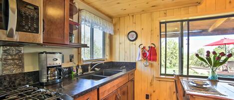 A kitchen with wooden cabinets, a stove, a coffee maker, and a sink.
