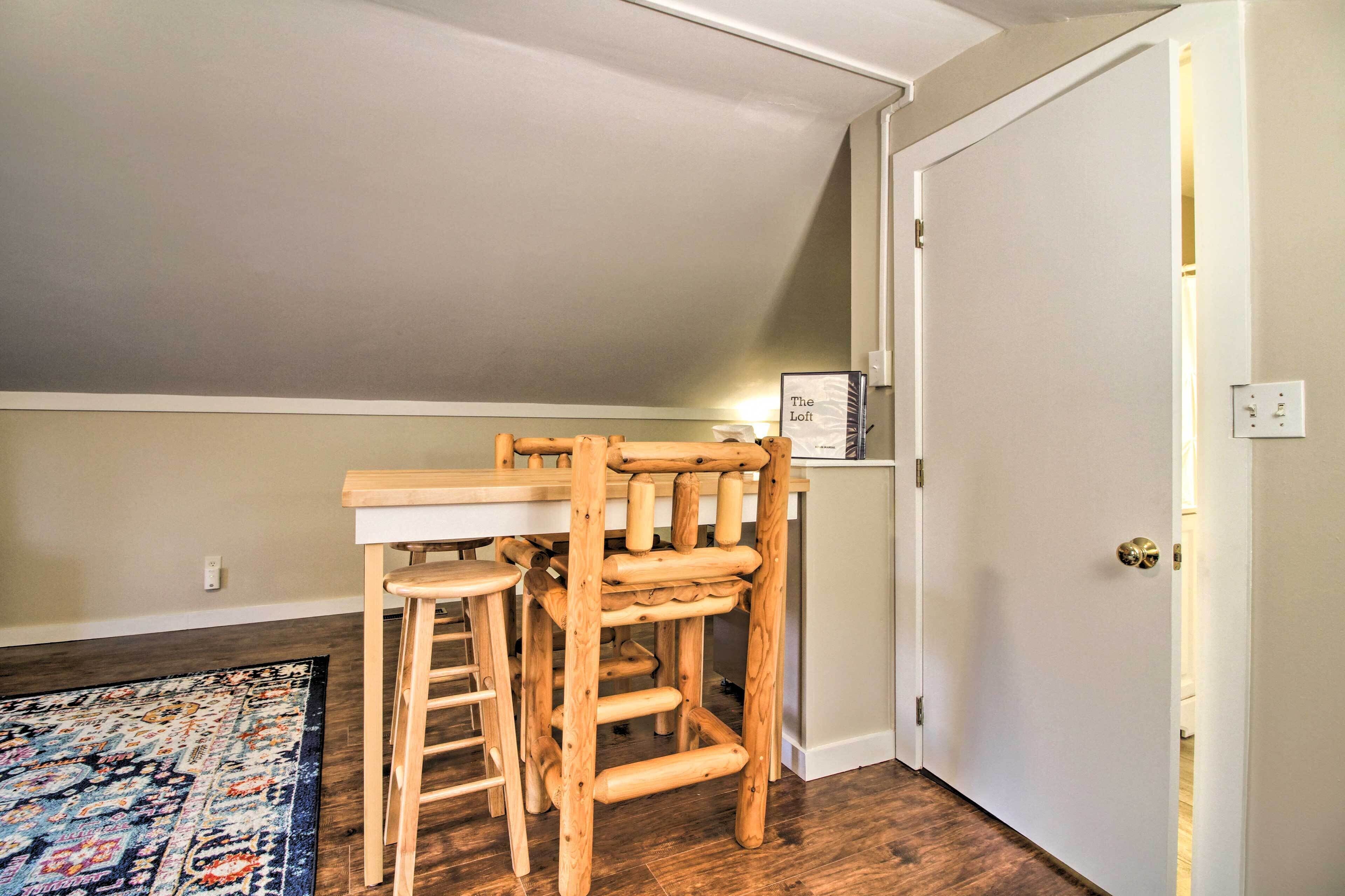 A corner room with a wooden chair and table, a patterned rug, and a door with a sign above it.