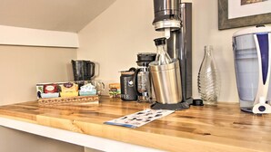 Een aanrecht met een koffiezetapparaat, een waterfles en een koffiemolen.
