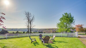 Vehreä ulkoalue, jossa on valkoinen puinen aita, pöytä ja tuolit sekä näkymä maaseudulle.