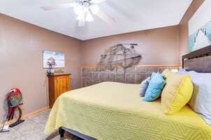Un dormitorio con una cama, un ventilador de techo, un armario de madera y una obra de arte en la pared.