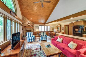 A spacious living room with a fireplace, a television, a red sofa, and a dining area with wooden furniture. - Private Dock & Stunning Views: Corey Lake Getaway! (Three Rivers)