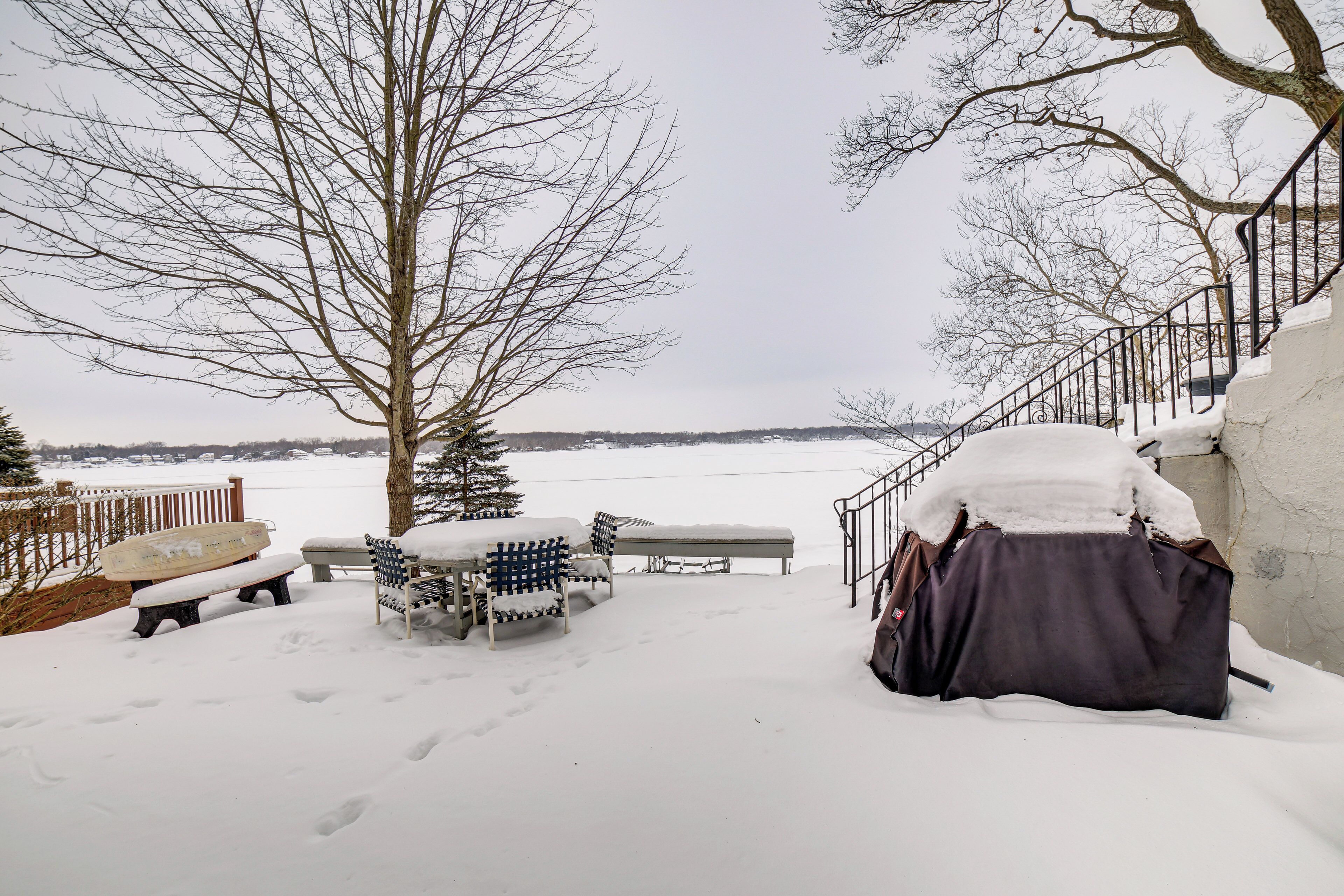 A snow-covered outdoor area with a bench, a table, and a covered object.