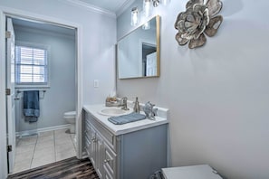 Une salle de bain avec un meuble-lavabo blanc, un grand miroir et un élément décoratif mural.