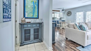 Una cocina moderna con una isla grande, una zona de comedor con una mesa y sillas blancas, y una sala de estar con un sofá color beige.