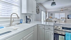 Una cocina moderna con armarios blancos, horno empotrado y cafetera.