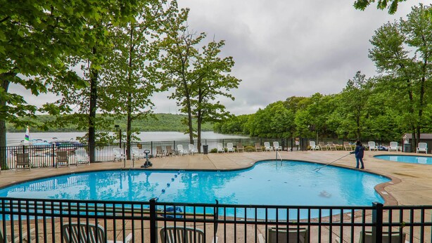 A swimming pool with lounge chairs and a person cleaning it. - Lake Harmony Villa: Walk to Big Boulder Mountain! (Lake Harmony)