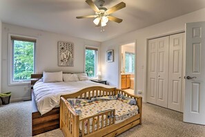 Une chambre avec un lit en bois, un ventilateur de plafond et une vue sur l’extérieur par une fenêtre.