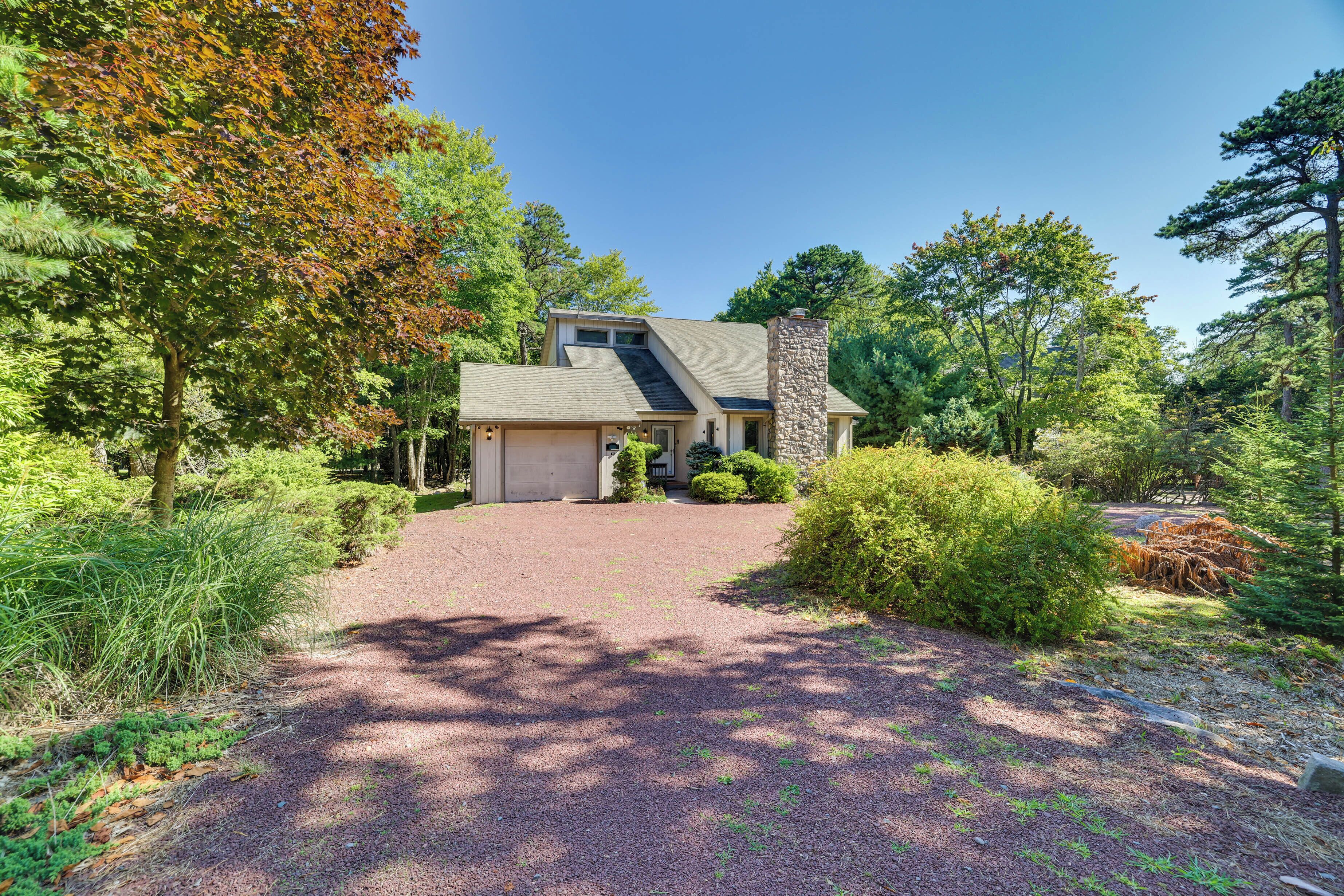 A house with a stone chimney, a gravel driveway, and a well-maintained garden.