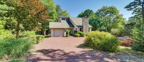 A house with a stone chimney, a gravel driveway, and a well-maintained garden.