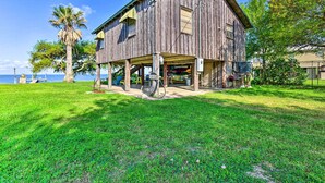 A rustic wooden house with a covered porch, a palm tree, and a view of the ocean.