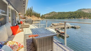 Una terraza con sofá, una parrilla y vistas al lago y a las embarcaciones amarradas.