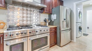 Una cocina con electrodomésticos de acero inoxidable, armarios de madera y salpicadero de azulejos.