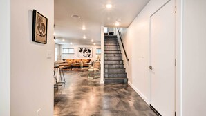 A modern interior with a staircase leading to a second floor, a living area with a sofa and chairs, and a polished concrete floor. - Modern Missoula Home ~ 2 Miles to Downtown! (Missoula)