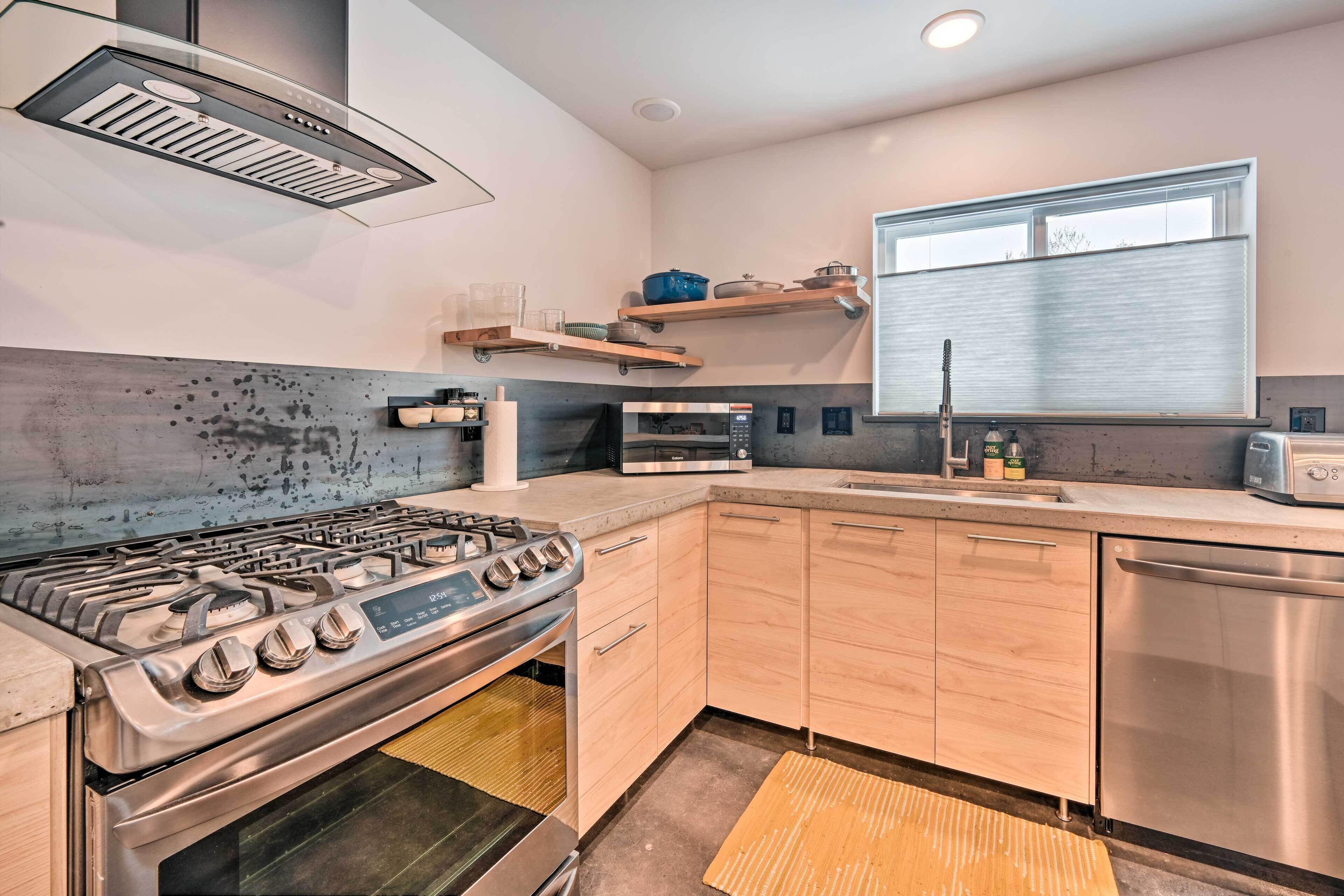 A modern kitchen with stainless steel appliances, wooden cabinets, and a window with blinds.