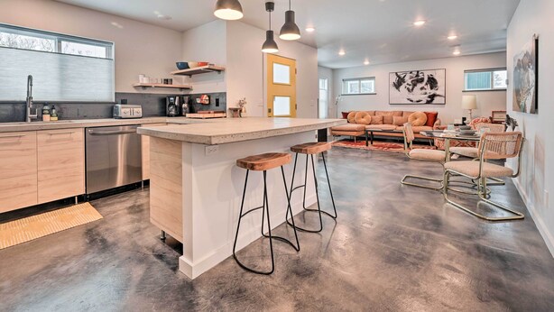 A modern kitchen with a central island, bar stools, and a dining area with a sofa and chairs. - Modern Missoula Home ~ 2 Miles to Downtown! (Missoula)