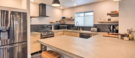 A modern kitchen with stainless steel appliances, a large island, and pendant lighting.