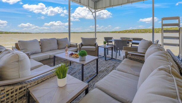 Una terrazza esterna con posti a sedere, tavoli e vista sull'acqua.