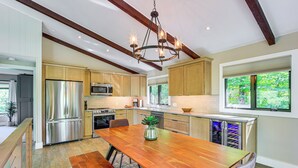 Een moderne keuken met houten kastjes, roestvrijstalen apparatuur en een grote houten eettafel.
