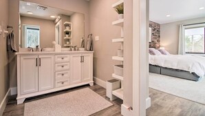 Een moderne badkamer met een grote spiegel, witte kastjes en een douchehoek.
