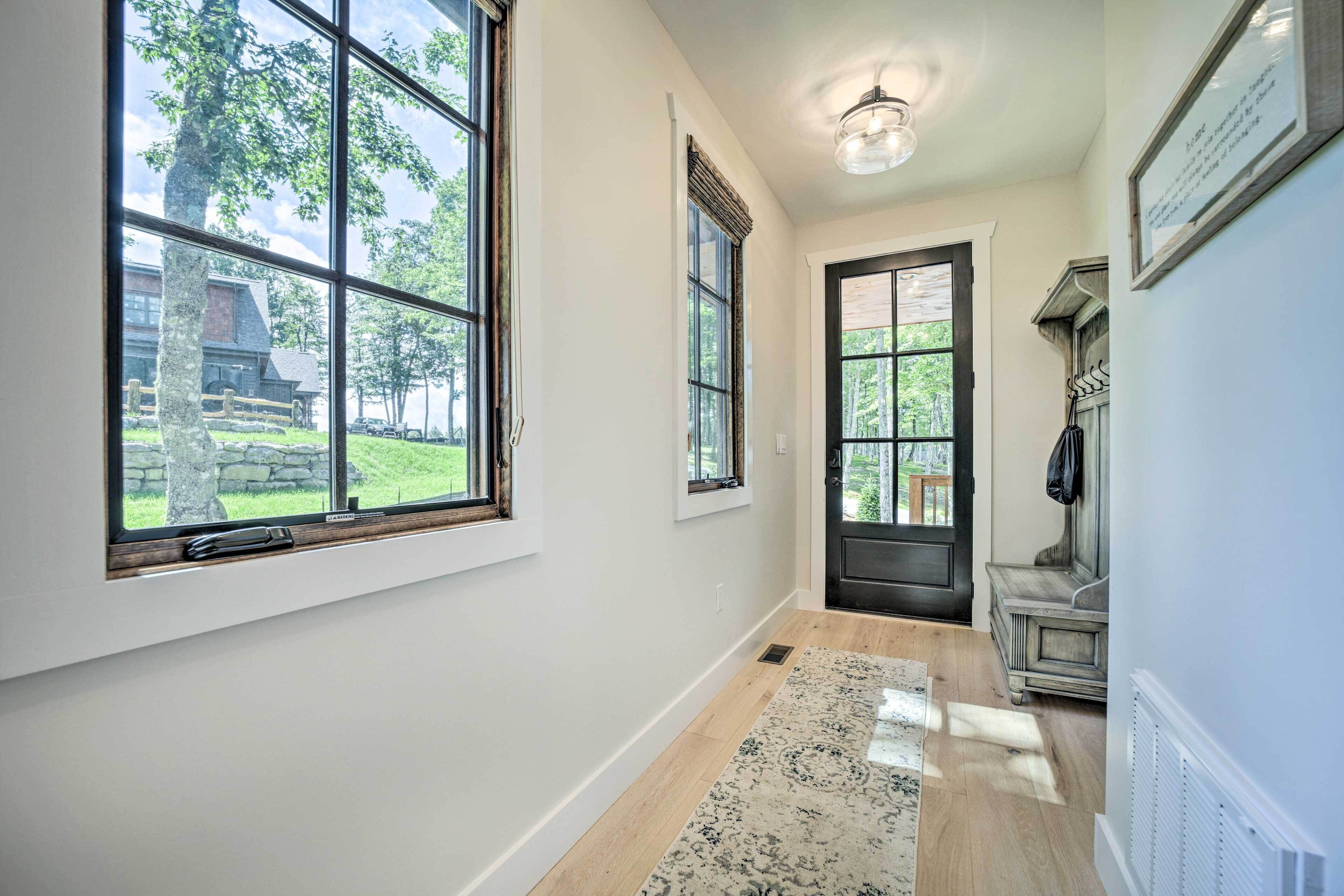 A hallway with large windows, a dark door, and a radiator on the wall.