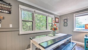 A dining area with a bench, a table with a placemat, and a vase with flowers. - Lakefront Hideaway w/ Dock, Kayaks, Fire Pit! (Glennie)