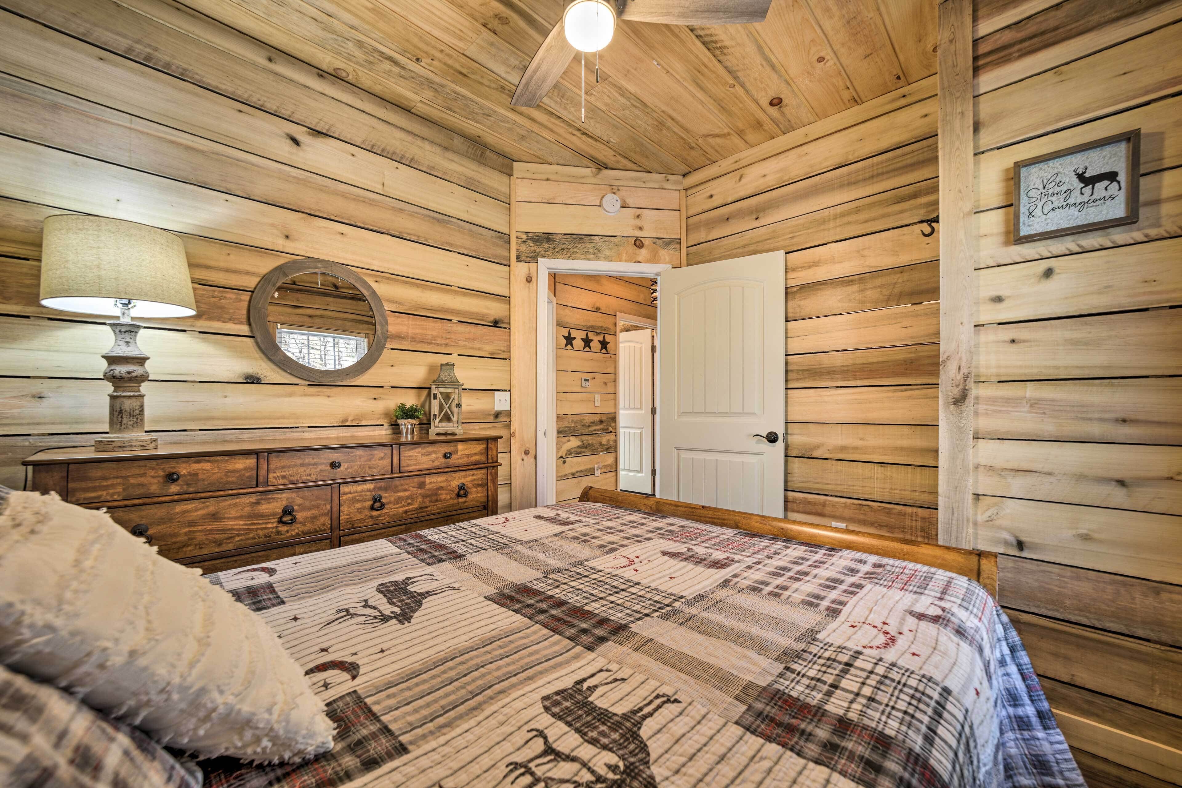 Un dormitorio con paneles de madera, una cama, un aparador, un espejo y una puerta que da a otra habitación.