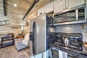 A kitchen with a stainless steel refrigerator, microwave, and stove. There is a wooden ceiling and a sofa with a patterned cushion. - Modern Cabin w/ Fire Pit < 3 Mi to Trails! (Pisgah Forest)