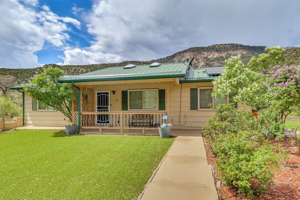 A two-story building with a green roof, a covered porch, and a view of a mountain. - Mom's Place in Jemez - 1 Mi to Hot Spring (Jemez Springs)