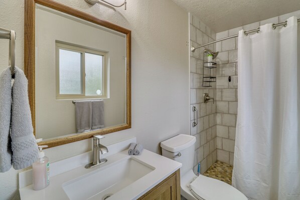 A bathroom with a sink, mirror, toilet, shower, and a window. - Mom's Place in Jemez - 1 Mi to Hot Spring (Jemez Springs)