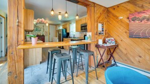 Eine Küche mit Holzwänden, einer Bar mit Hockern und hängenden Pendelleuchten.