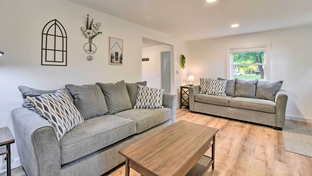 A modern living room with two grey sofas, a wooden coffee table, and a large window providing a view of greenery outside. - Centrally Located Mount Pleasant Retreat! (Mount Pleasant)